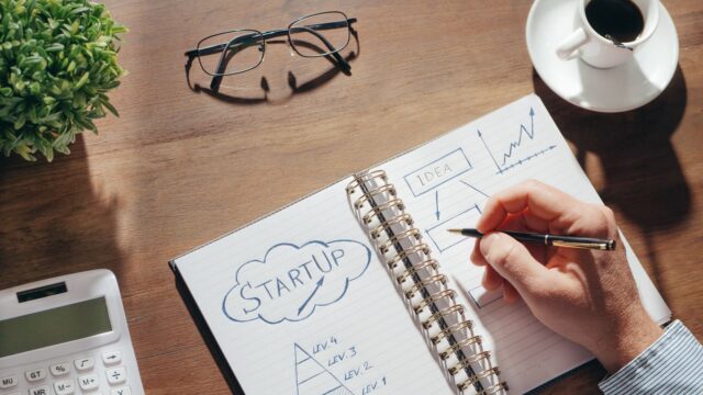 ノートに事業計画を書き込む様子