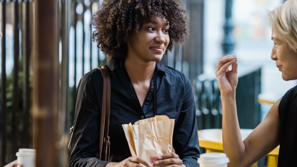カフェのテラス席で会話をする二人の女性